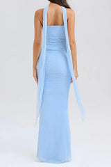Back view of a woman in a light blue strapless ruched mesh gown with a long flowing scarf detail cascading down.