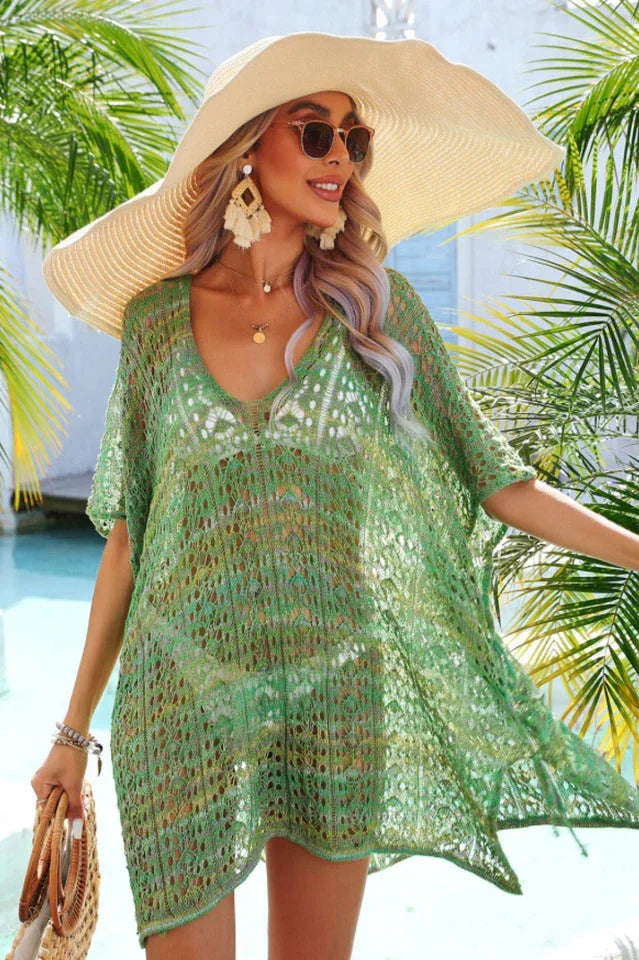 Woman wearing a green crochet knit kaftan cover-up with a wide-brimmed hat and sunglasses.