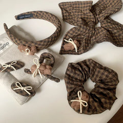 assortment of brown plaid hair accessories, featuring scrunchies, headbands, clips, and barrettes with teddy bear embellishments