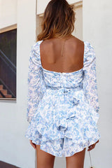 Back view of a white and blue floral print mini dress with long sleeves and a sweetheart neckline, showing a bow detail.
