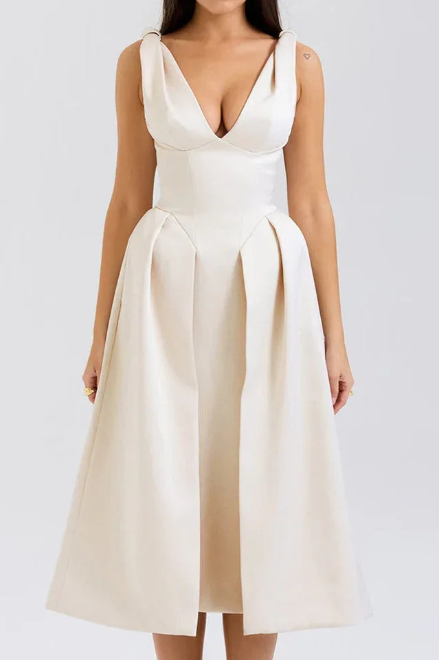 Woman wearing an ivory midi dress with a deep V-neck and pleated skirt.