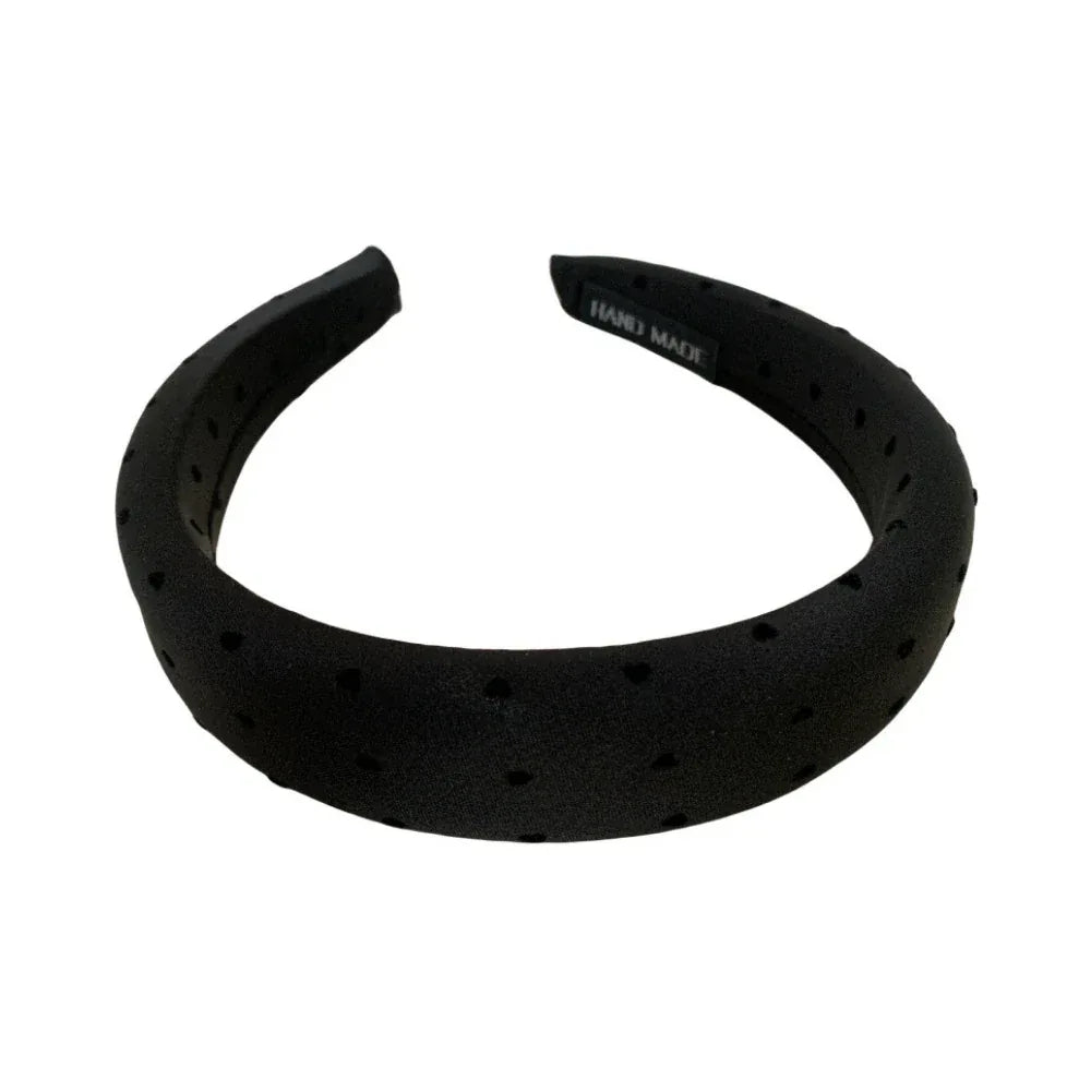 A black puffy headband with a scattered heart print.
