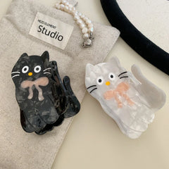White and black marbled cat hair clips with pink bows and fabric pouch