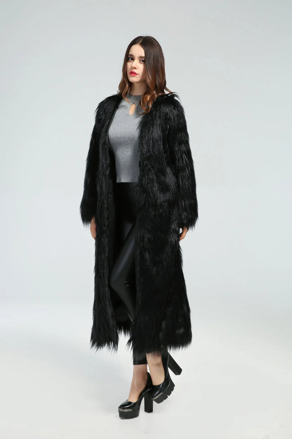 Woman standing in a long black faux fur coat, angled slightly