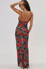 Woman wearing a long floral print dress with spaghetti straps and a cowl neckline, back view.