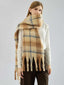 Woman wearing a tan and blue plaid fuzzy knit scarf with fringe detail.