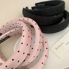 A collection of pink and black puffy headbands with a heart print.