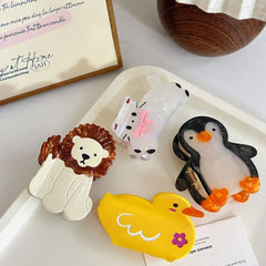collection of animal hair claw clips including a cat, lion, penguin, and duck on a white tray