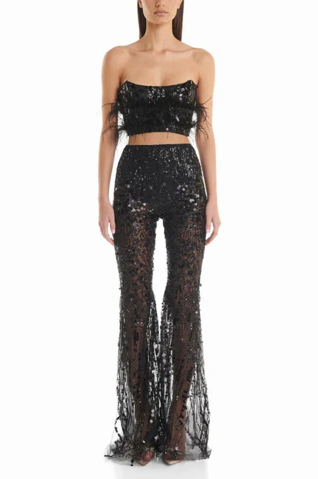 Woman wearing a black sequined two-piece outfit with feather trim and flared pants, front view.