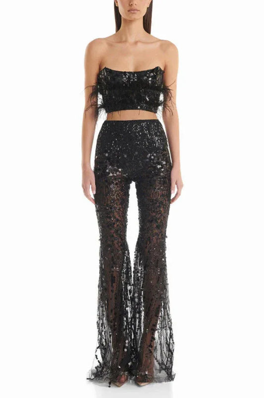 Woman wearing a black sequined two-piece outfit with feather trim and flared pants, front view.