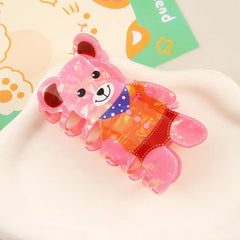 Pink iridescent bear-shaped hair claw clip with a detailed outfit, shown from a side angle