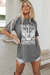 Woman wearing a grey graphic t-shirt with 'Nashville Music City Tennessee' and a guitar with wings design, paired with denim shorts.