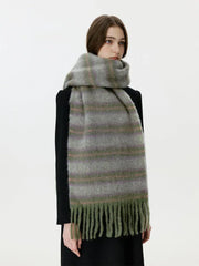 Front view of a woman wearing a black coat and a fuzzy, striped scarf with fringe detail.