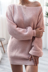Woman with arms crossed wearing a pink off-the-shoulder ribbed knit tunic sweater.