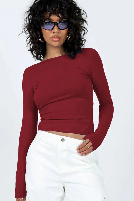Woman wearing a long-sleeve maroon crop top and white cargo pants, front view.