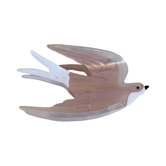 A pearlescent pink and white acrylic hair clip shaped like a swallow in flight against a white background.