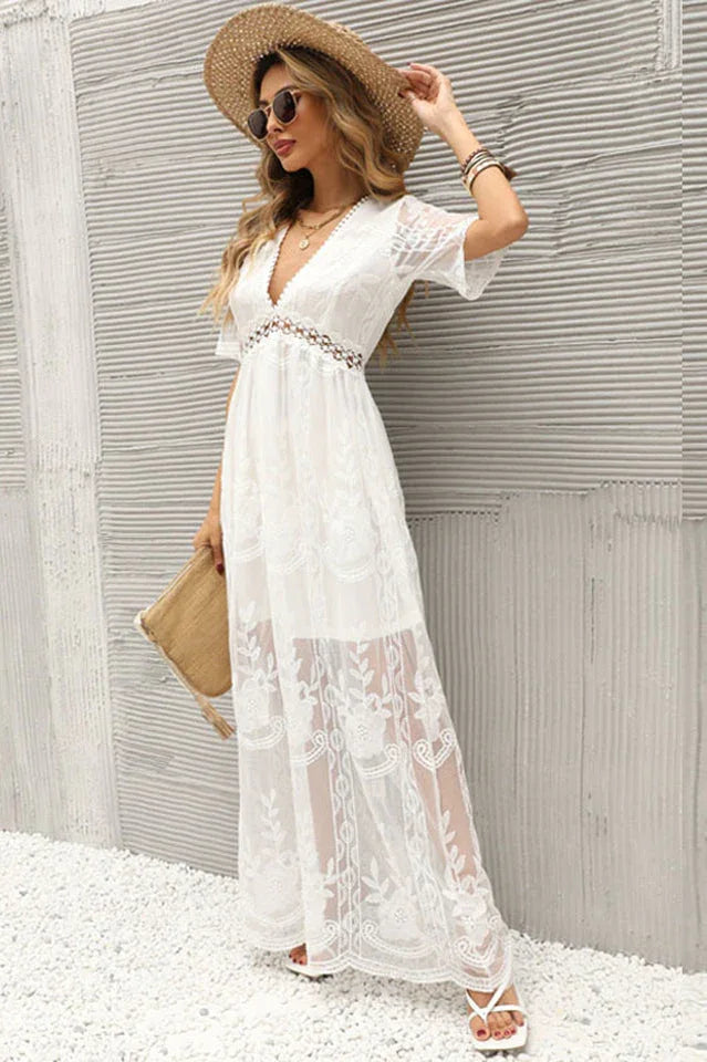 woman in a white lace maxi dress wearing a straw hat and holding a clutch