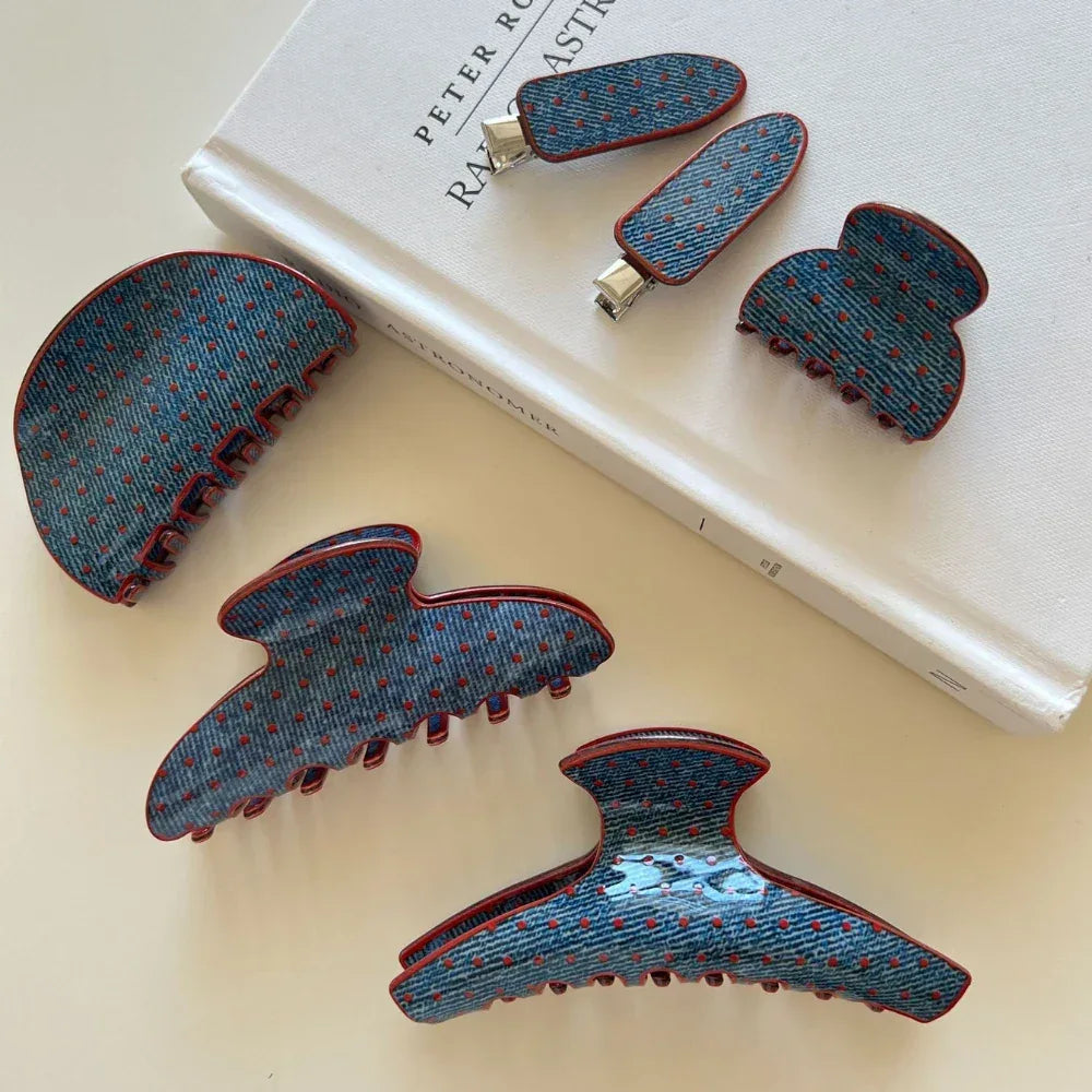Assortment of blue polka dot hair clips with red trim arranged on a book