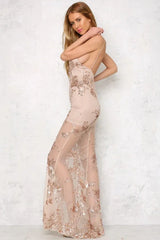 Woman in a long nude sequined and appliqued sheer dress with a high slit and deep V-neck, posing from the side