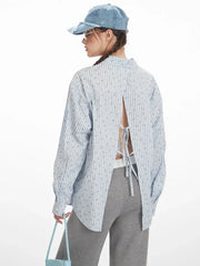 Close-up back view of the open-back detail on the light blue pinstripe shirt.