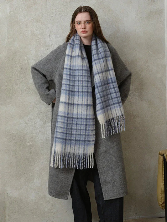 Woman wearing a grey coat and a blue and white plaid scarf.