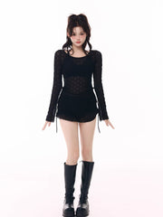 Model wearing a black sheer long-sleeve top, black shorts, and black platform boots.