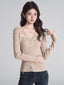 Woman wearing a beige ribbed knit cardigan with lace trim and a v-neck, paired with dark wash jeans.