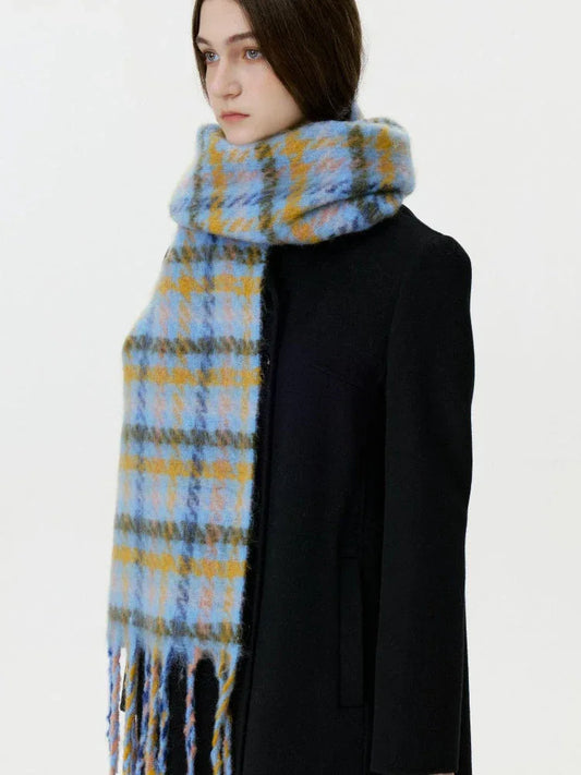 Woman wearing a black coat and a blue and yellow plaid scarf with fringe