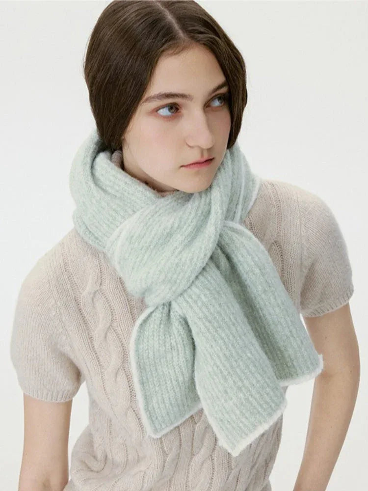 Close-up of a woman wearing a light green ribbed knit scarf with white trim