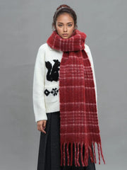 Front view of a woman modeling a white graphic sweater and a voluminous red plaid scarf.