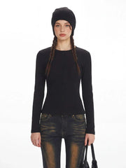 Close-up front view of a model wearing a black ribbed knit top and distressed flared jeans with fur trim cuffs.