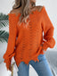 Woman wearing an orange distressed off-the-shoulder knit sweater with blue jeans.