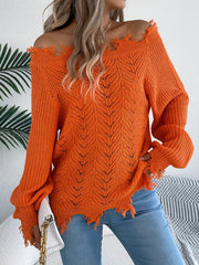 Woman wearing an orange distressed off-the-shoulder knit sweater with blue jeans.