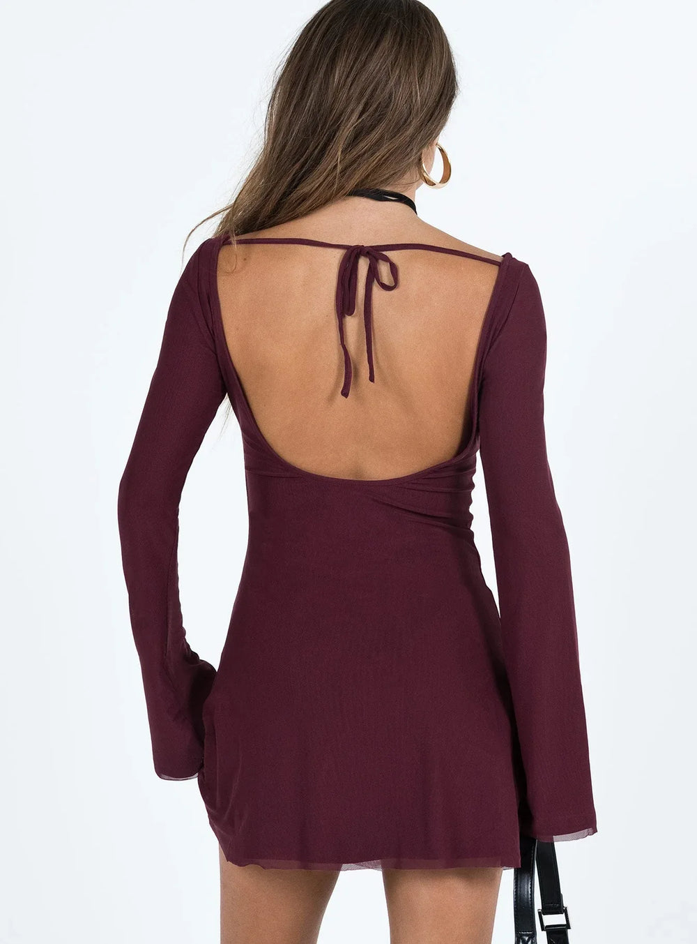 Back view of a burgundy long sleeve mini dress with an open back and tie closure