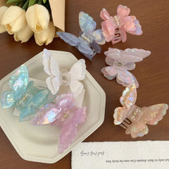 Collection of iridescent butterfly claw clips in various pastel colors arranged on a tray and a table