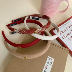 Close-up of padded headbands in red, beige, white, and plaid with a pink mug and book