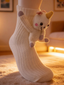 Close-up of a white knit crew sock with a plush unicorn attached to the side, resting on a textured rug.