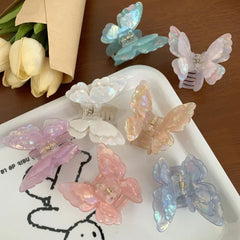 Pastel iridescent butterfly claw clips scattered on a white tray with tulips in the background