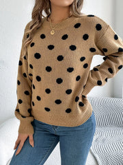 Woman wearing a brown polka dot sweater with blue jeans, side view.