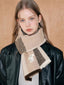 Young woman wearing a plaid knit scarf around her neck.