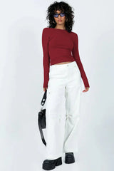 Woman wearing a long-sleeve maroon crop top and white cargo pants, full body view.