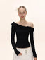 Model wearing a black off-the-shoulder long-sleeved top with ruffle trim, paired with white wide-leg pants.