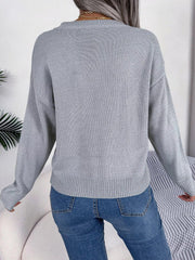Back view of a woman wearing a grey knit sweater with blue jeans.