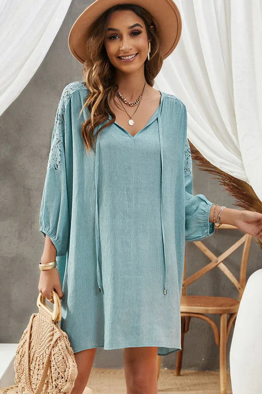 Woman wearing a light blue bohemian-style dress with lace sleeves and a straw hat