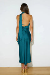 Back view of a woman in a teal satin halter midi dress with a tie detail.