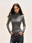 Woman wearing a grey long-sleeve turtleneck top and dark wash jeans, hands in pockets.
