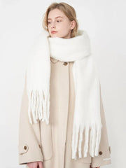 Woman wearing a white fluffy scarf draped over a beige coat, side profile