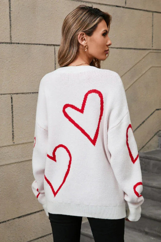 Back view of a woman wearing a white knit sweater with a red heart print.