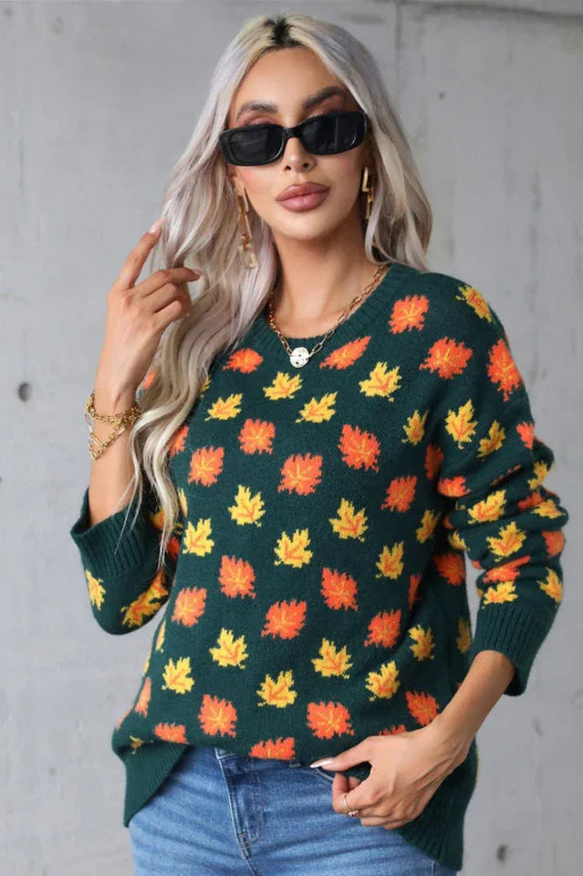 Front view of a woman in a dark green knit sweater with a maple leaf print. She is accessorizing with sunglasses and a gold necklace.