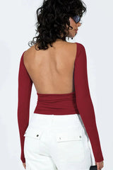 Woman wearing a long-sleeve maroon crop top and white cargo pants, rear view showing open back detail.